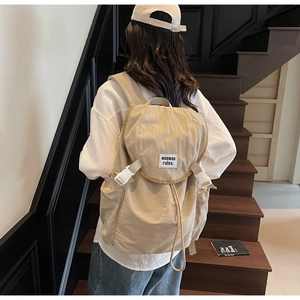 Detail of khaki casual backpack showing flap closure and adjustable long drawstrings