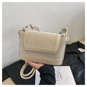 Detail of beige crossbody bag with mesh texture, knotted strap and gold brand logo