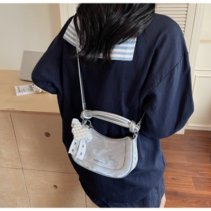 Silver metallic dumpling bag with pearl bow charm shown in a lifestyle setting