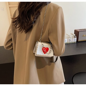 Detail of silver patent mini crossbody bag with red heart and metallic bead chain strap
