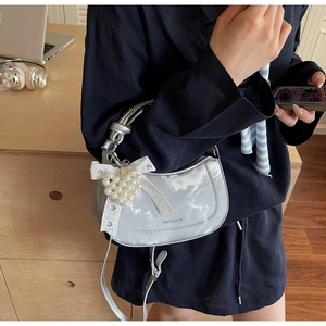 Detail of silver saddle bag with white lace bow and heart pearl pendant on strap