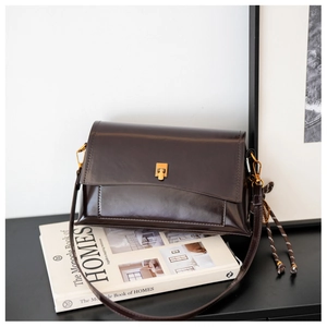 Détail du sac carré en cuir ciré marron foncé avec boucle dorée et pendentif tissé élégant