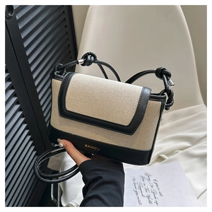 Detail of beige canvas and black leather crossbody bag with BAIKOU gold logo and rope strap