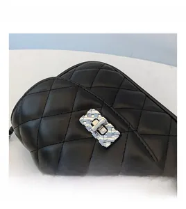 Close-up of silver twist lock with woven texture on black quilted leather crossbody bag