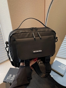 Minimalist black nylon crossbody messenger bag with adjustable strap and double zipper detail