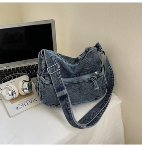 Detail of retro washed denim tote with functional multi-zipper pockets and wide strap