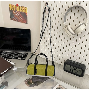 Mini cylindrical running crossbody bag with woven texture shown in a lifestyle desk setup