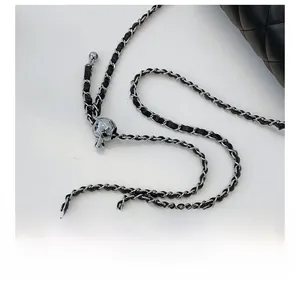 Detail of adjustable silver ball buckle and black leather woven chain strap on a quilted bag