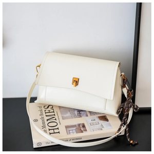 Détail du sac en cuir ciré blanc crème avec fermoir doré et pendentif tressé