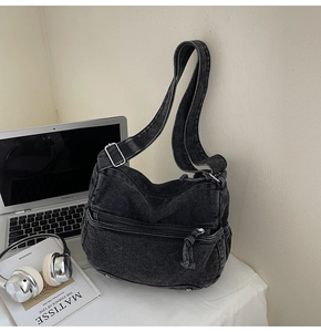 Detail of washed black denim crossbody bag with adjustable strap and front zipper pocket