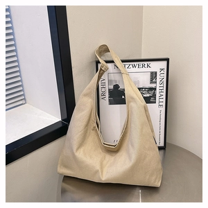 Minimalist beige canvas hobo bag placed on a modern stainless steel desk background