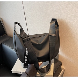 Detail of a black hobo bag with wide nylon strap displayed on a white stand