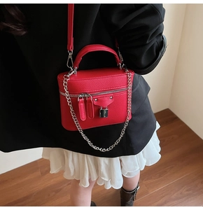 Detail of red lychee leather texture on a fashion bag with silver lock and chain strap