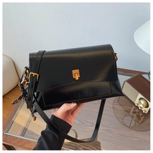 Détail d'un sac à bandoulière vintage en cuir noir avec un fermoir carré doré brillant