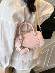 Chic pink leather Boston bag with a heart pendant shown in a side-view style
