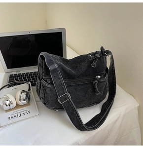 Detail of black washed denim crossbody bag with thick rope zipper pulls and side pockets