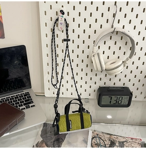 Detailed close-up of a mini neon green crossbody bag with black braided rope strap