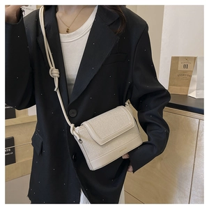 Detail of cream canvas crossbody bag with PU leather trim and BAIKOU brand logo