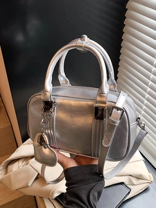Metallic silver Boston bag with heart charm and top handle shown in a lifestyle setting