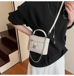 Detailed view of white litchi pattern leather mini bag with silver chain and lock buckle