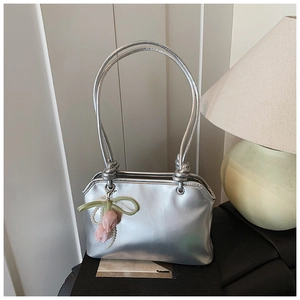 Detail of silver metallic handbag with unique knot handles and a pink tulip pearl charm