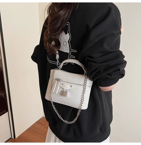 Detail of white litchi pattern small square bag with silver lock and metal chain strap