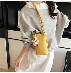 Yellow bucket bag with pebble texture and cute duck charm shown in a modern home setting
