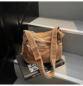 Detail of heavy washed canvas crossbody bag with metal buckles and multiple pockets