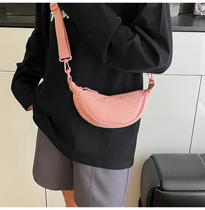 Detail of pink nylon dumpling crossbody bag with adjustable wide shoulder strap on model