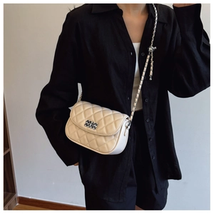 Close-up of cream quilted crossbody bag with chain strap worn by a female model