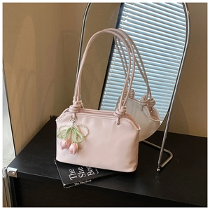 Detail of light pink shoulder bag featuring a pearl tulip charm and knot strap design