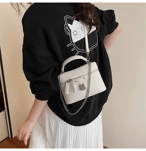 Detail of minimalist beige pebbled leather crossbody bag with silver lock and chain