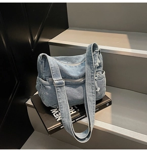 Macro detail of washed light blue denim crossbody bag with side pocket and silver hardware