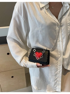 Mini black crossbody bag with red heart detail and silver bead chain on white shirt