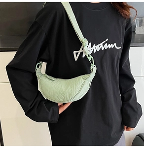 Close-up of a light green nylon crescent crossbody bag with adjustable strap and zipper