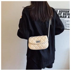 Detailed view of cream quilted chain bag with silver twist lock on model in indoor setting