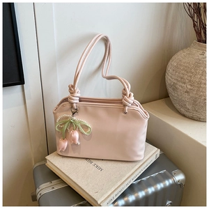 Detail of pink shoulder bag with tulip pearl pendant and knotted handle on book stand