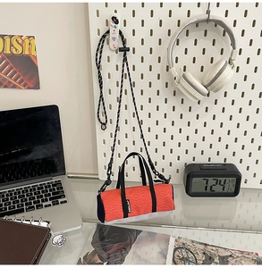 Detailed view of an orange mini cylinder running bag with a polka dot rope strap