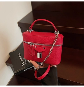 Detail of red pebbled leather vanity bag with silver chain and metal lock on books