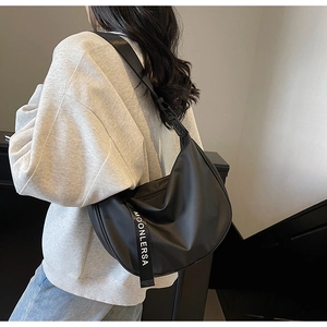 Detailed back view of a black crescent nylon crossbody bag on a model showing drape