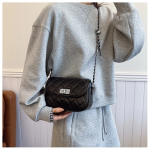 Close-up of black quilted crossbody bag with silver rotating lock and chain strap