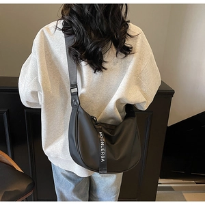 Detailed back view of a black nylon crescent hobo bag with a wide gray shoulder strap