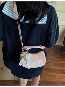 Pink crescent crossbody bag with pearl heart charm and bow detail on model