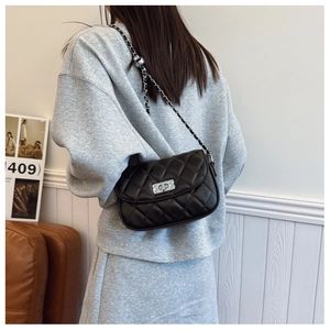 Detail view of black quilted chain strap shoulder bag with silver hardware on a model