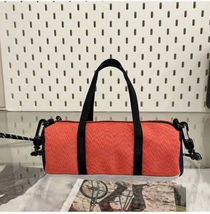 Detail view of mini cylindrical running bag with orange canvas and durable gray bottom