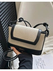 Minimalist beige woven canvas crossbody bag with black leather trim and knot strap detail