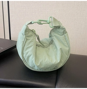 Detail of mint green nylon crescent bag featuring matching plastic hook and zipper closure