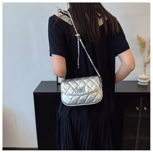 Detail of silver quilted crossbody bag with adjustable gold-ball chain and metal lock