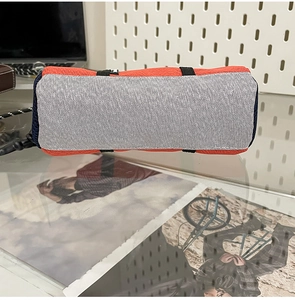 Detail of orange nylon and grey mesh storage bag showing breathable texture and durable strap