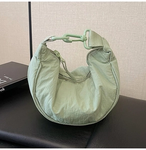 Detailed close-up of light green nylon crescent bag with textured folds and matching zippers